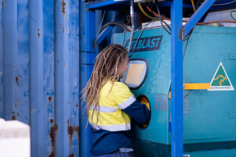 sbting1 Technician from a powdercoating services company putting his hands inside a sand blasting machine