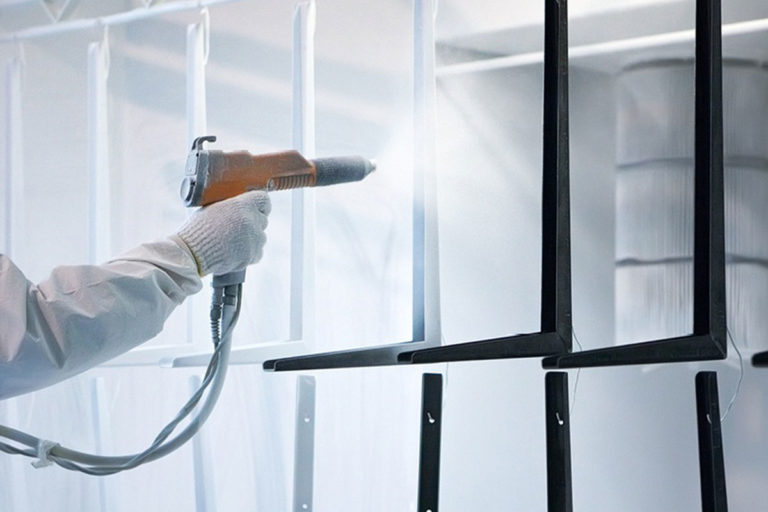 Technician from a powdercoating services team working powder coating pieces of metals