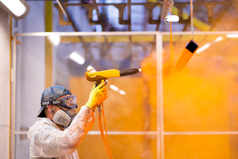 Technician from a powdercoating perth company powdercoatng a piece of metal