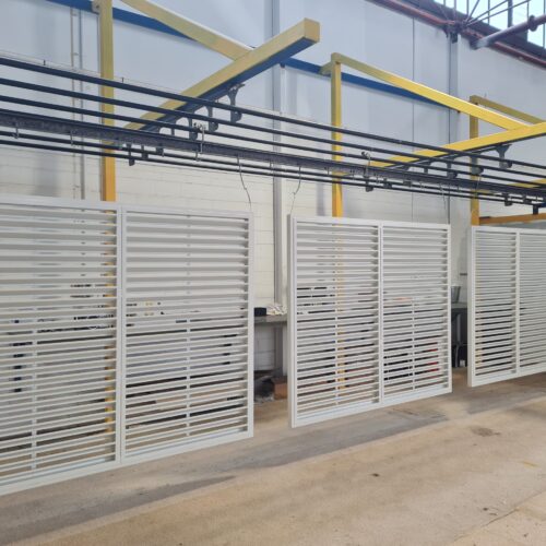 A large room adorned with numerous white shutters, representing the environment of Precision Powdercoating