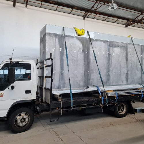 A truck parked in Precision Powdercoating warehouse, loaded with a large container