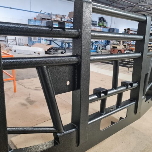 A large black metal frame supports a substantial piece of metal, a finish spray painting services of Precision Powdercoating