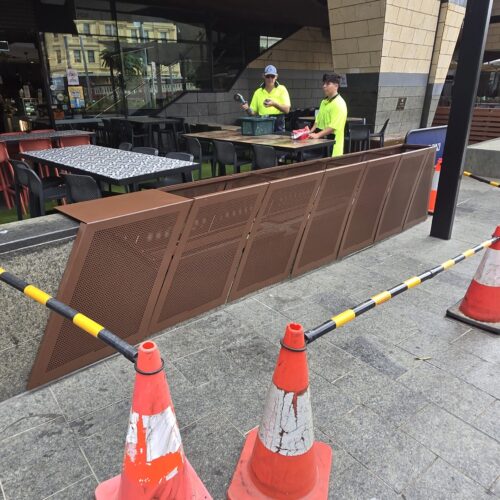 Two men meticulously works on a large chocolate piece, showcasing his skills at Precision Powdercoating
